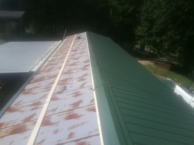 Old rusted panels beside newly installed green metal roofing — Wind Damage Roof Repair by Roofing Brothers in Little Silver