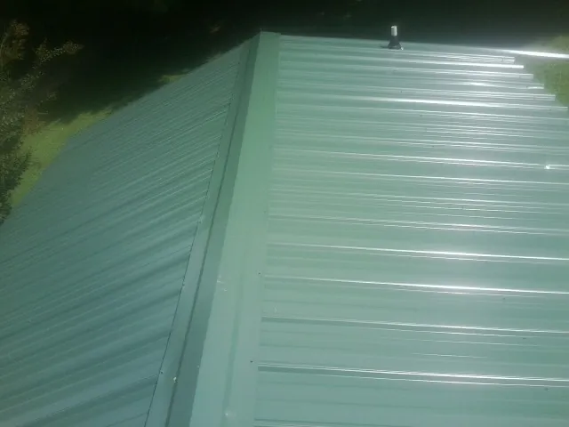 New green metal panels meeting at the ridge of a roof — Flat Roof Repair work by our crew in Little Silver