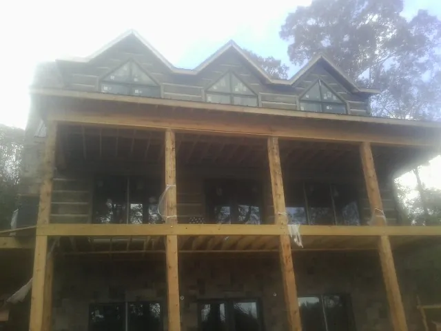 Dormers and porch framing on a large log home under construction — Roof Coating work by our crew in Little Silver