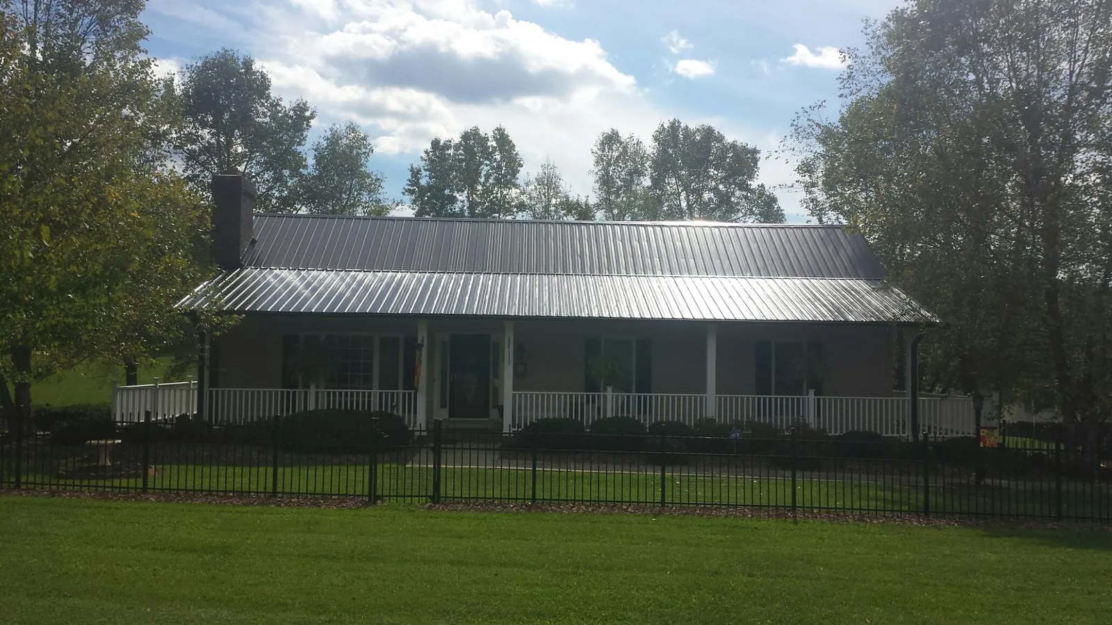 Gray metal roof on a brick ranch with a full width front porch — Gutter Guard Installation work by our crew in Little Silver