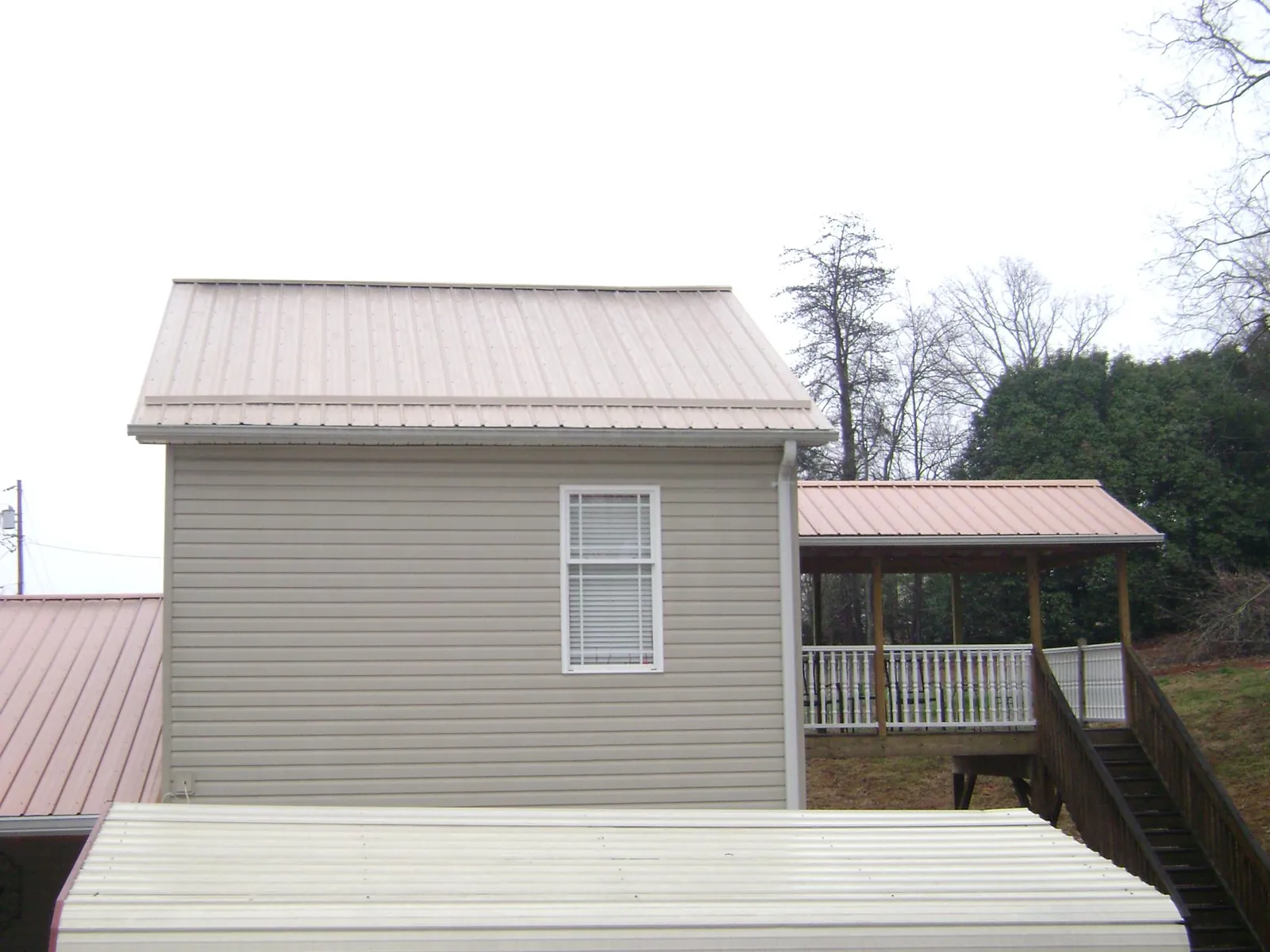 Tan metal roofs on a two story addition and attached porch, from a Roof Replacement job in Little Silver