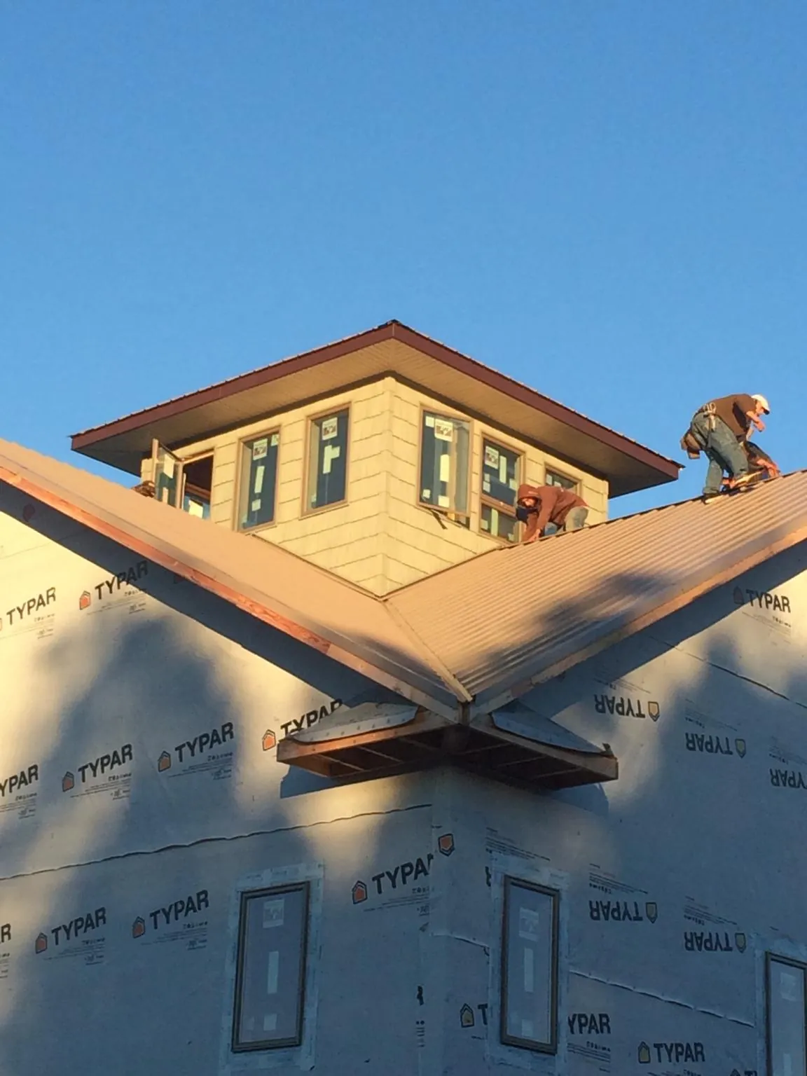 Roofers working around a rooftop cupola on a new metal roof at sunset — Roof Waterproofing in Little Silver by Roofing Brothers